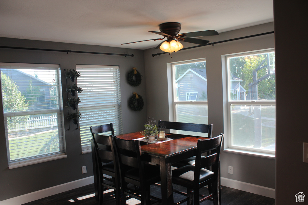 Dining space with healthy amount of natural light, baseboards, dark wood-style flooring, and a ceiling fan