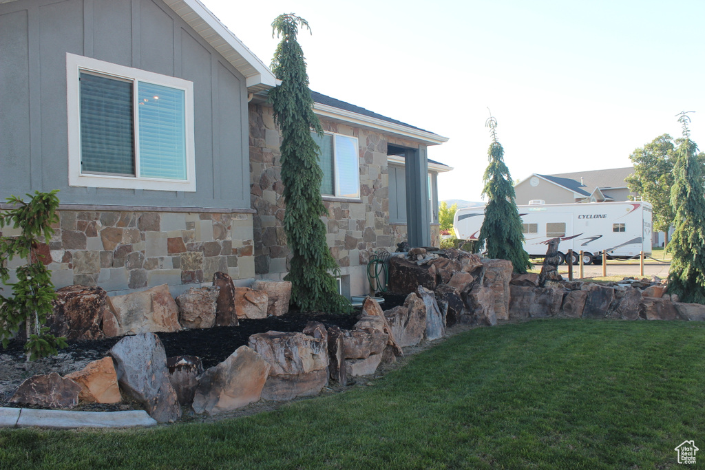 View of side of home featuring stone siding, a lawn, and board and batten siding