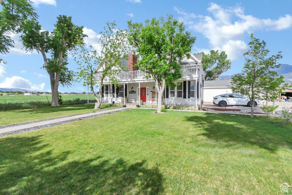 Neoclassical / greek revival house with covered porch, a front yard, and a chimney