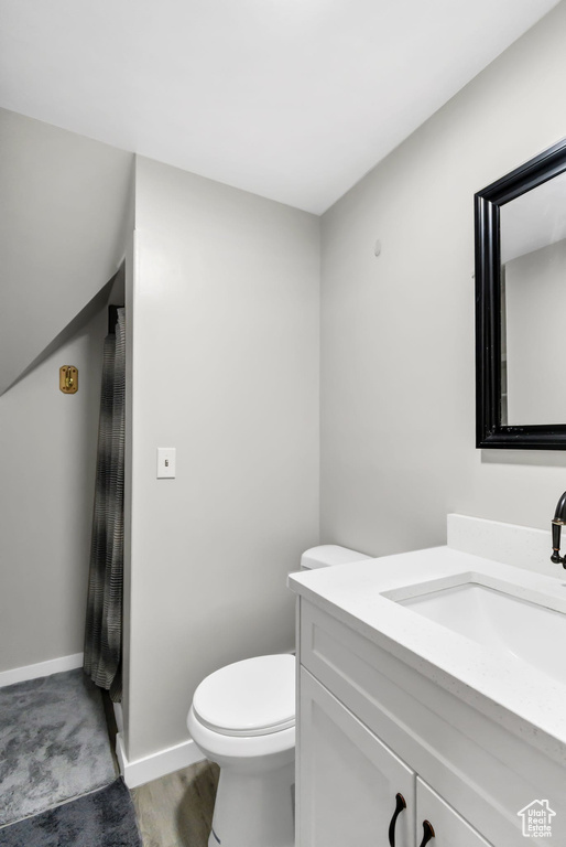 Bathroom featuring vanity, toilet, and baseboards