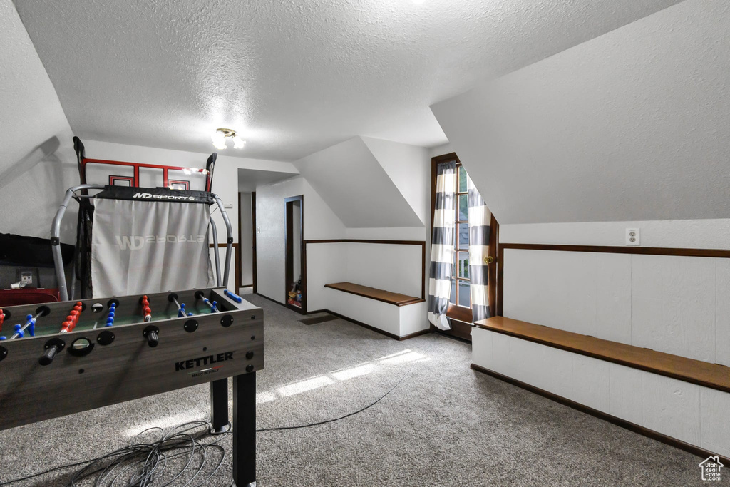 Game room featuring carpet floors, a textured ceiling, and vaulted ceiling