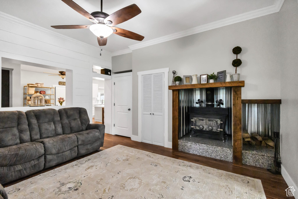 Living room with a ceiling fan, ornamental molding, wood finished floors, baseboards, and a fireplace