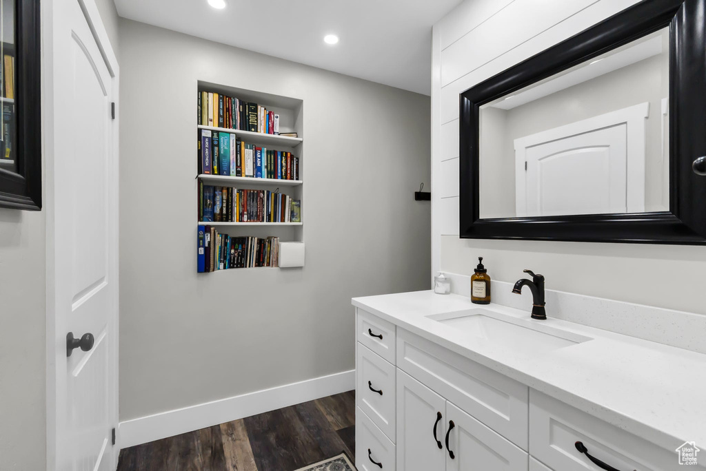 Bathroom featuring vanity, wood finished floors, baseboards, and recessed lighting