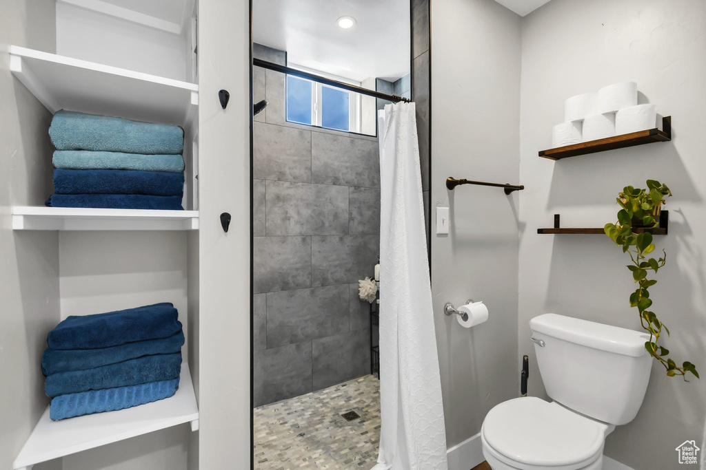 Bathroom featuring toilet, a shower stall, and baseboards