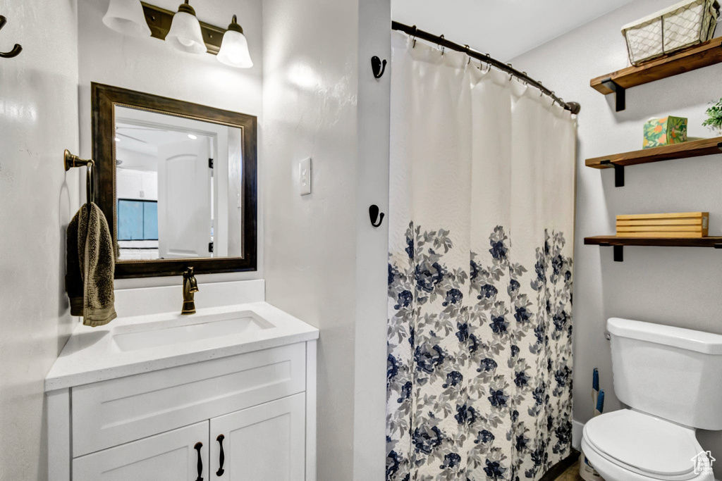 Bathroom featuring toilet, vanity, and a shower with shower curtain