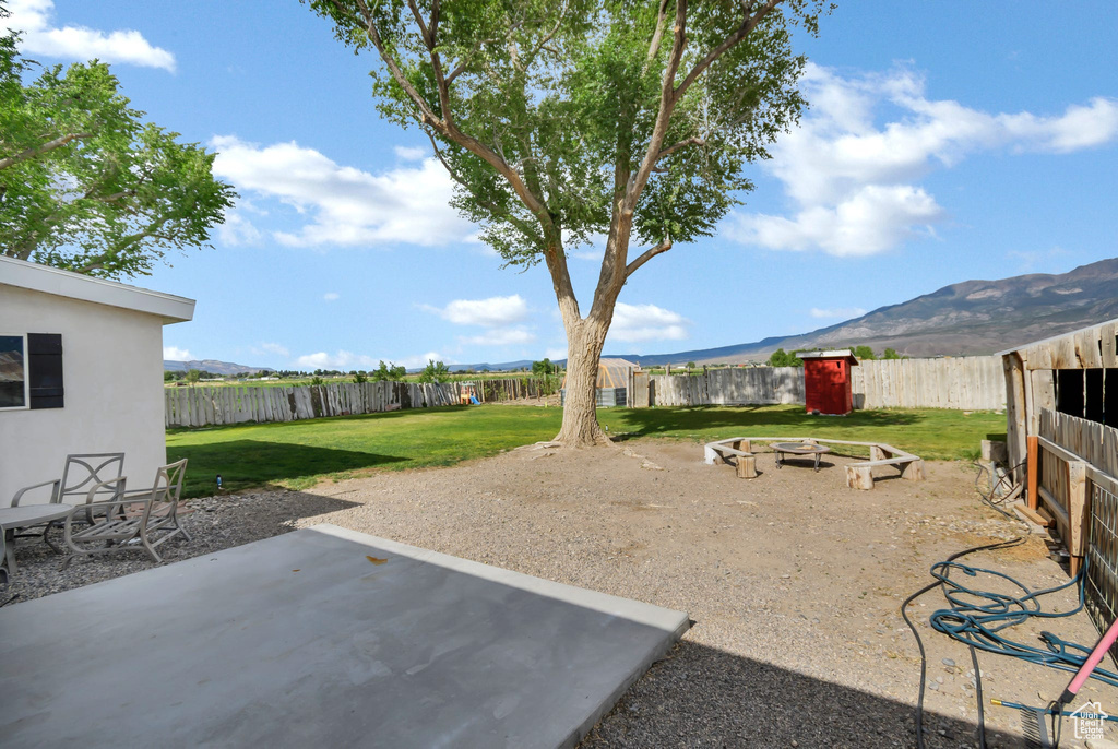 View of yard featuring a fire pit, a mountain view, and a patio