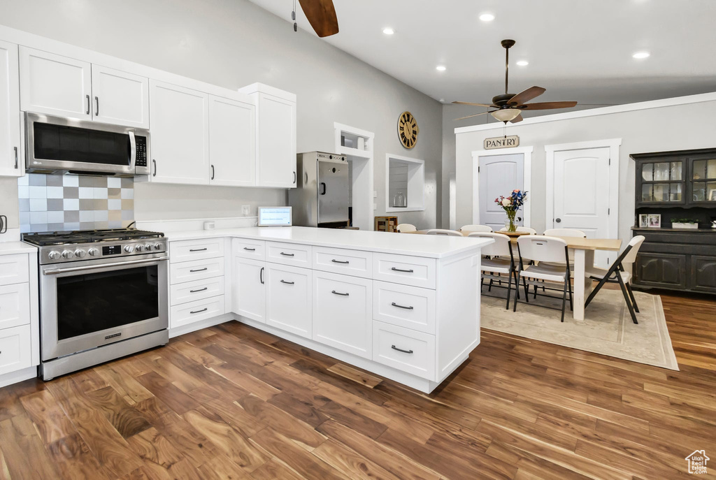 Kitchen with appliances with stainless steel finishes, ceiling fan, a peninsula, light countertops, and white cabinets