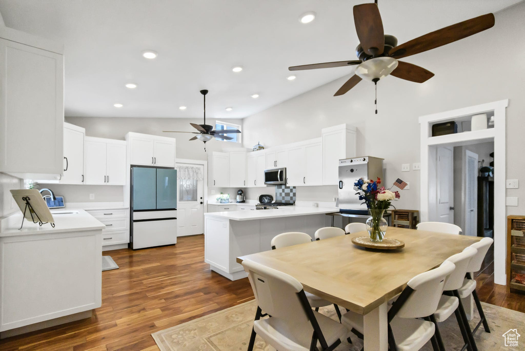 Dining room with a ceiling fan, high vaulted ceiling, wood finished floors, and recessed lighting