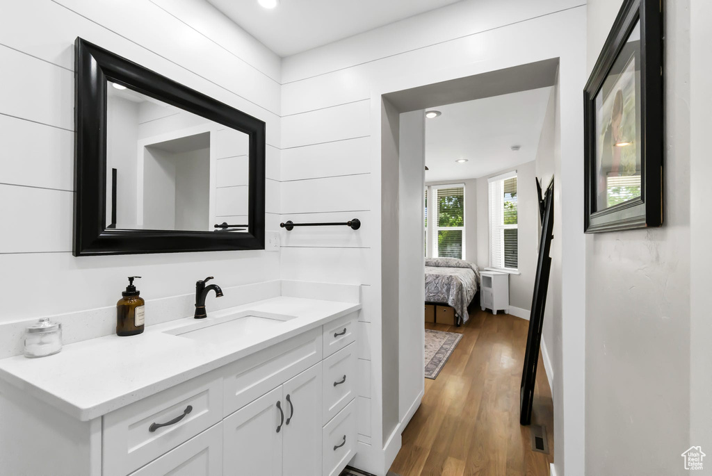 Bathroom with vanity, wood finished floors, radiator, baseboards, and recessed lighting