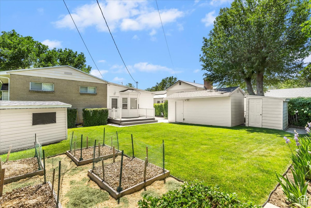 View of green lawn featuring a vegetable garden and a deck