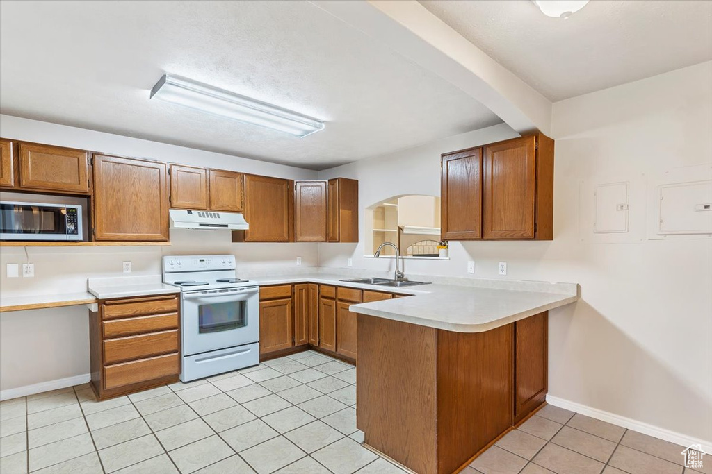 Kitchen featuring white electric range oven, under cabinet range hood, stainless steel microwave, a sink, and a peninsula