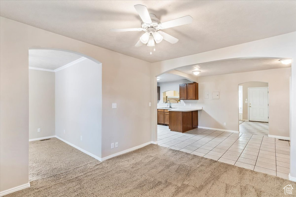 Kitchen featuring light carpet, light tile patterned floors, a ceiling fan, and arched walkways