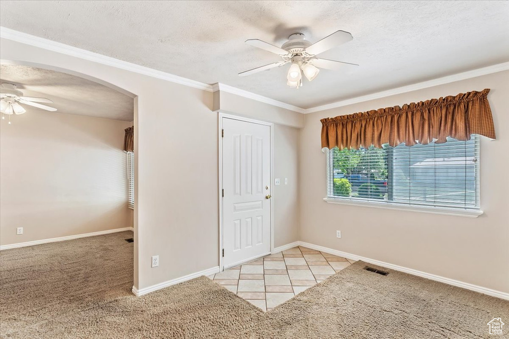 Unfurnished bedroom with arched walkways, baseboards, a textured ceiling, light carpet, and a ceiling fan