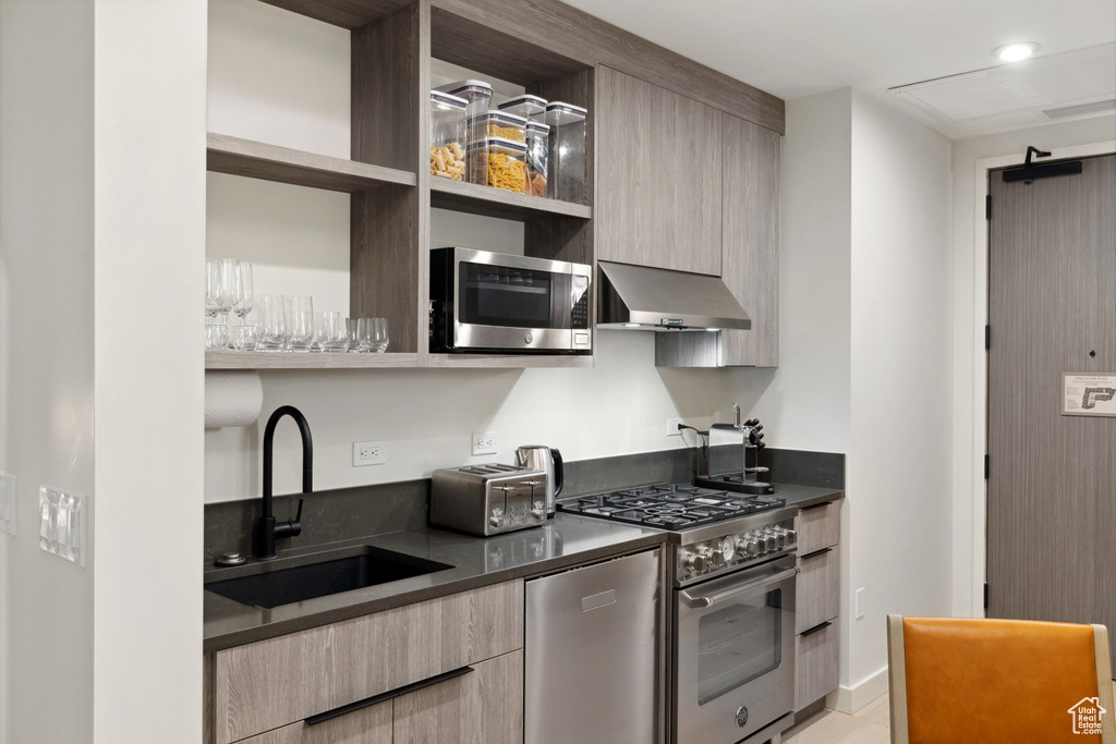 Kitchen with stainless steel appliances, extractor fan, open shelves, and a sink