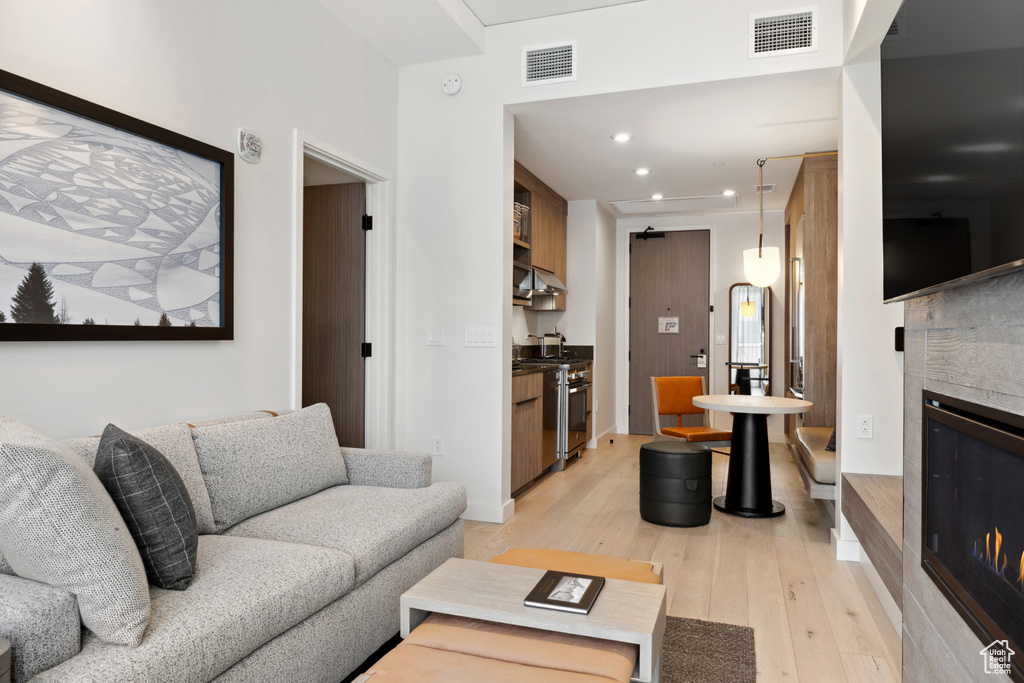 Living room featuring a glass covered fireplace, light wood-style flooring, recessed lighting, and baseboards