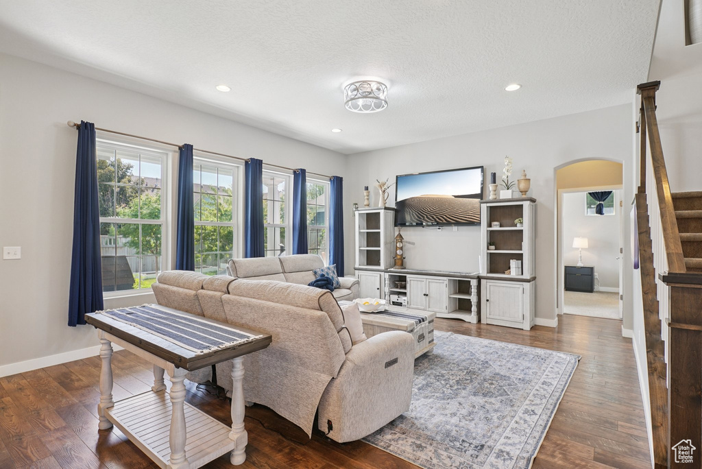 Living area featuring stairway, arched walkways, baseboards, recessed lighting, and dark wood-style flooring