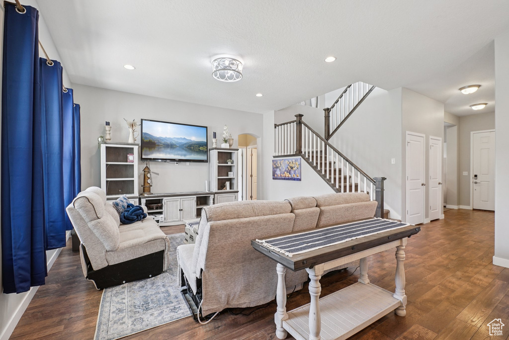 Living area with stairs, dark wood-style flooring, baseboards, and recessed lighting