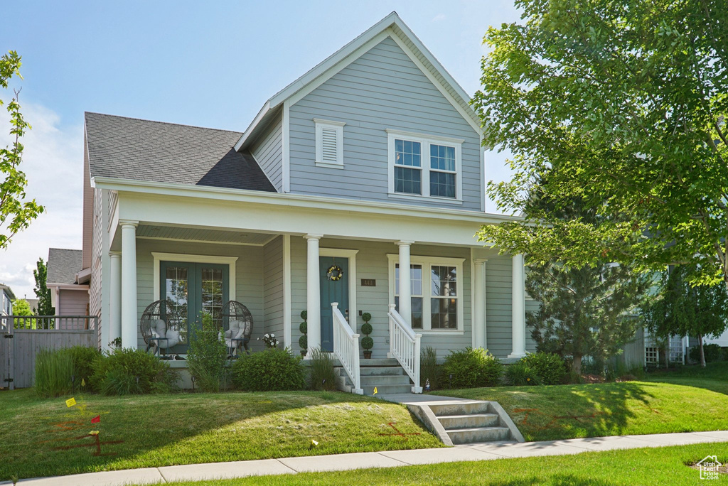 Traditional-style house with covered porch, a front lawn, and a shingled roof