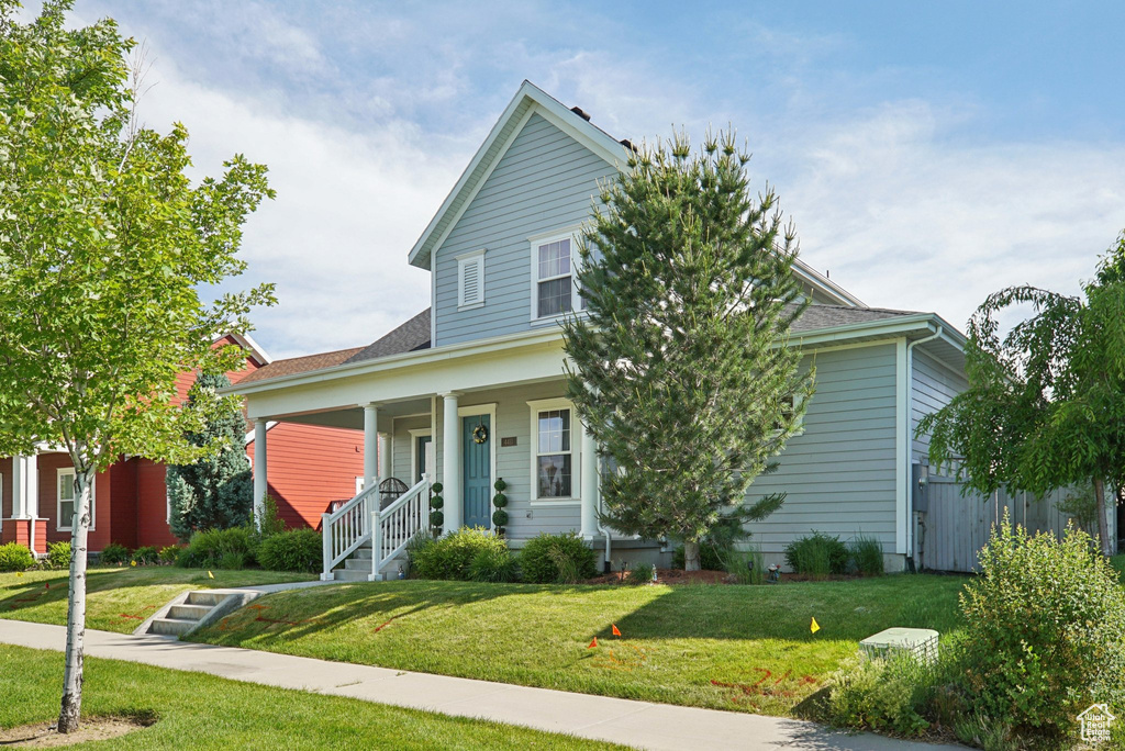 View of front of property with a porch, a front yard, and roof with shingles