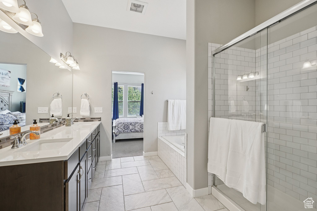 Bathroom featuring ensuite bath, marble look tile flooring, baseboards, and double vanity