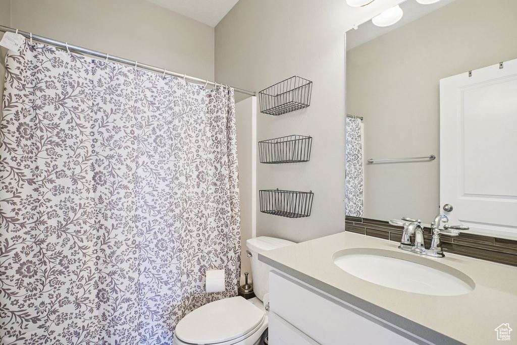 Full bath with vanity, toilet, and a shower with shower curtain