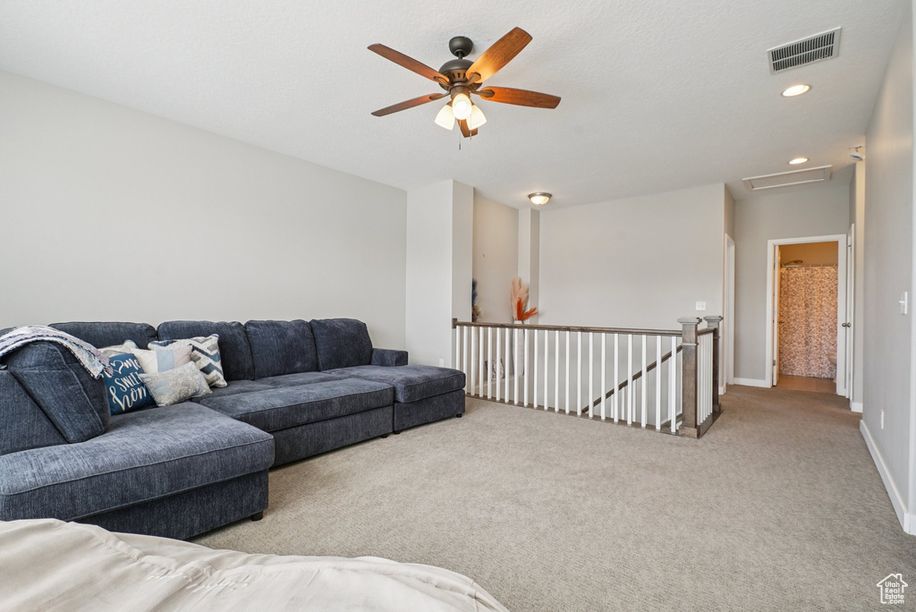 Carpeted living area with attic access, ceiling fan, baseboards, and recessed lighting
