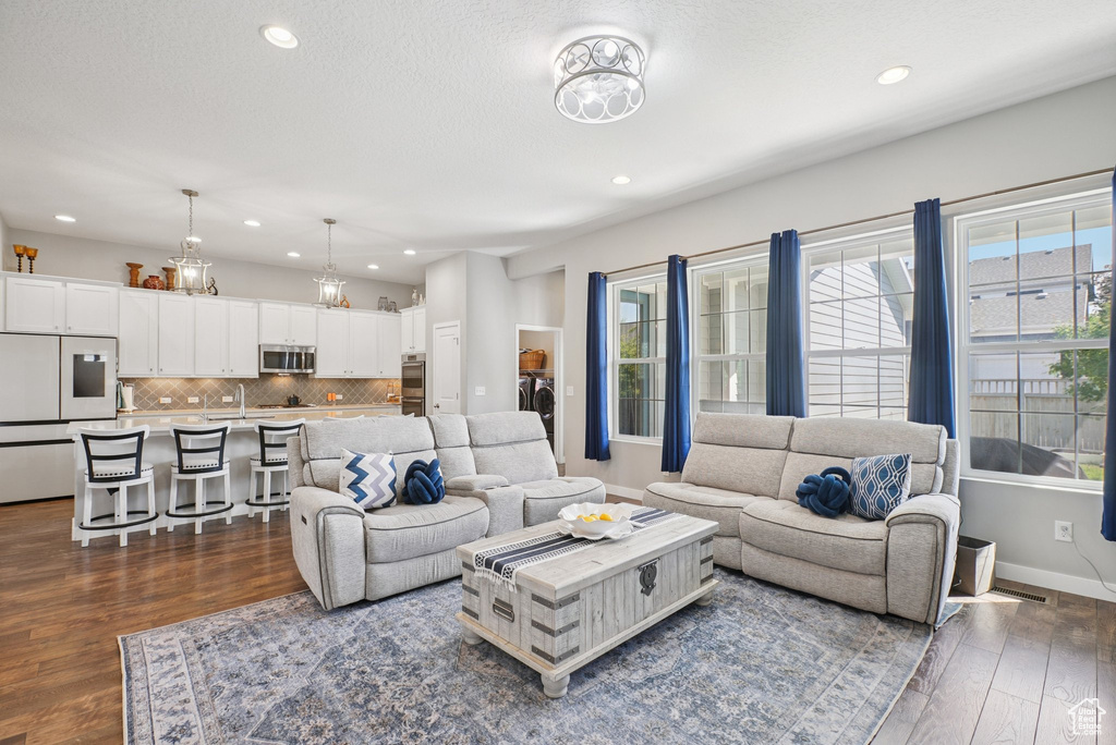 Living area featuring dark wood-style flooring, recessed lighting, and baseboards