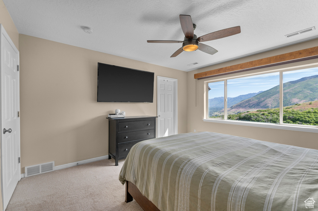 Bedroom with light colored carpet, baseboards, and a ceiling fan