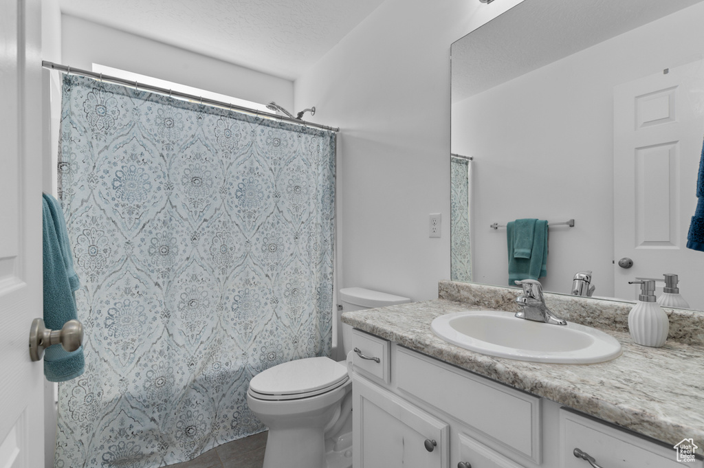 Full bathroom featuring vanity, toilet, curtained shower, and tile patterned flooring