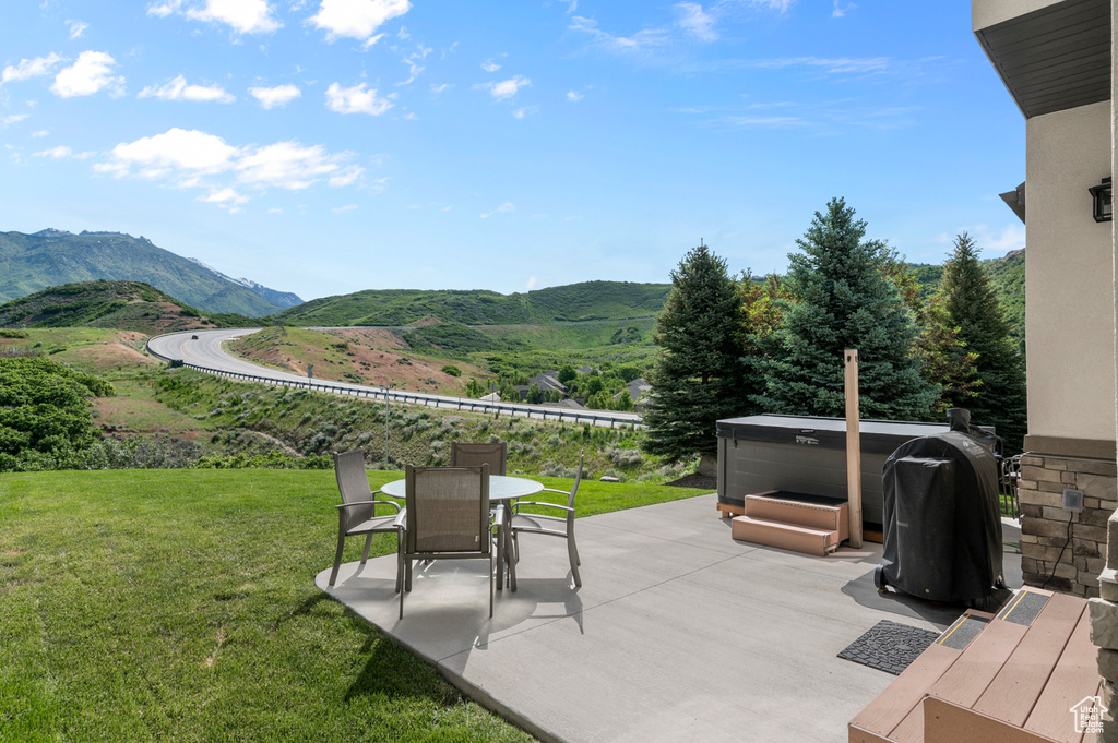 View of patio / terrace featuring a hot tub, a mountain view, outdoor dining space, and area for grilling