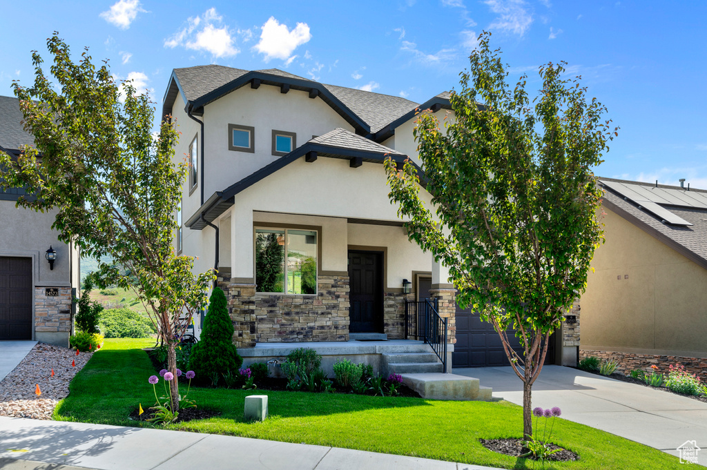 View of front of home featuring driveway, stucco siding, stone siding, and a garage