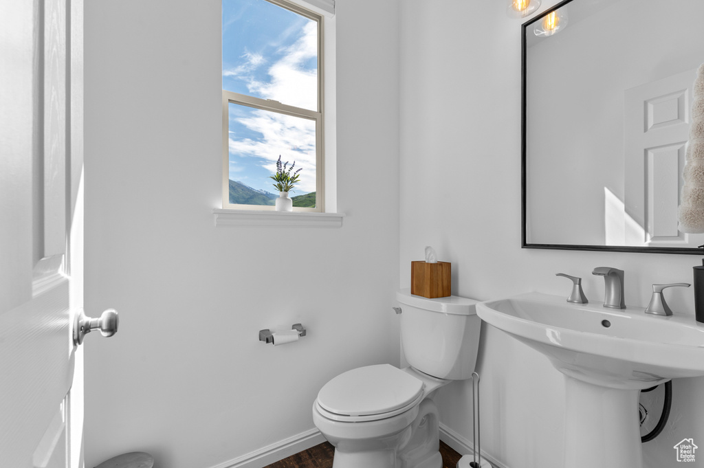 Half bathroom with baseboards, toilet, and a sink