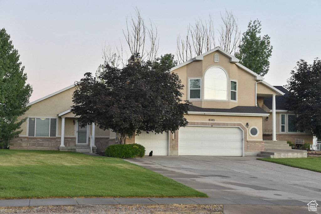 View of front of property with an attached garage, stucco siding, driveway, and a front yard