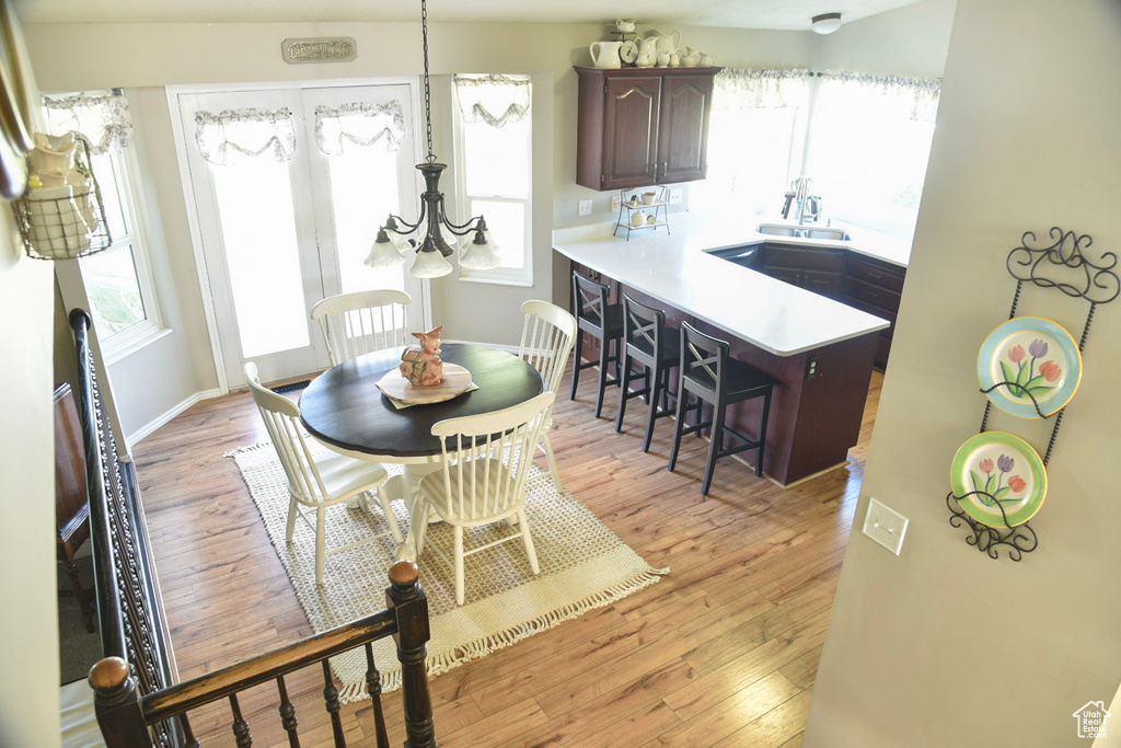 Dining area with healthy amount of natural light, light wood-type flooring, and a chandelier