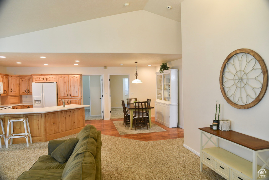 Living room with recessed lighting, light carpet, baseboards, high vaulted ceiling, and light wood finished floors