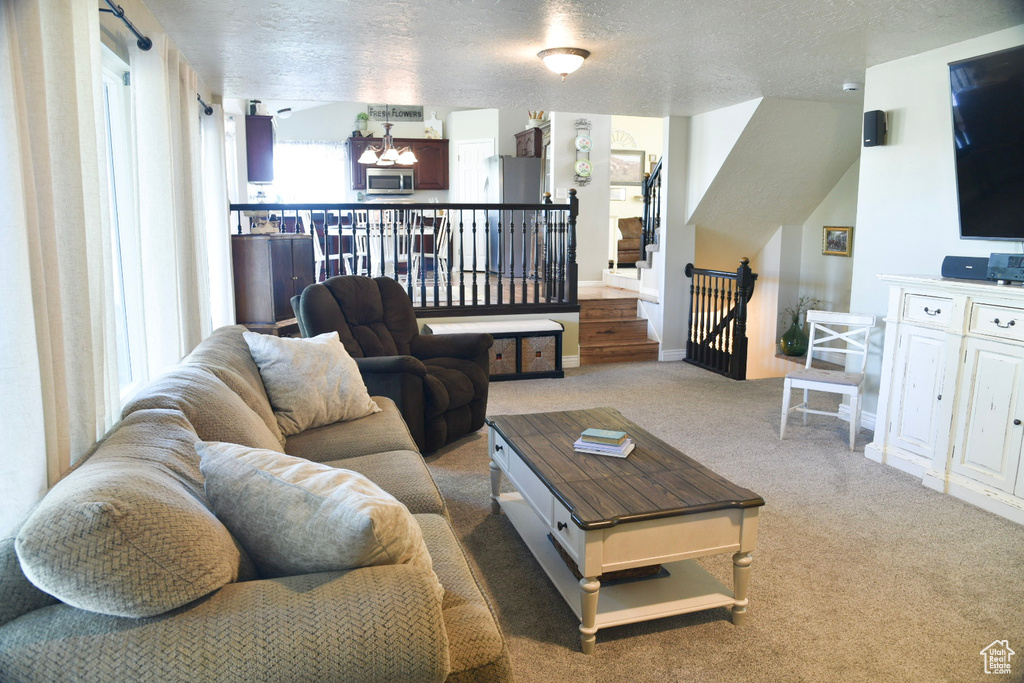 Carpeted living area with a chandelier, a textured ceiling, and baseboards