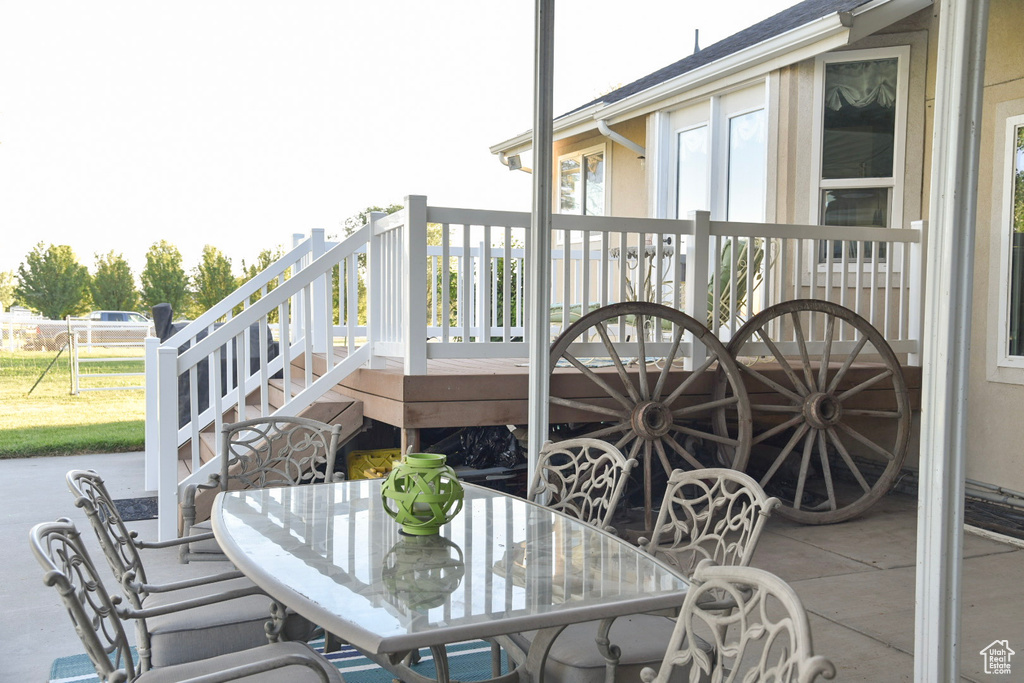 Wooden terrace featuring outdoor dining space, stairs, and a patio