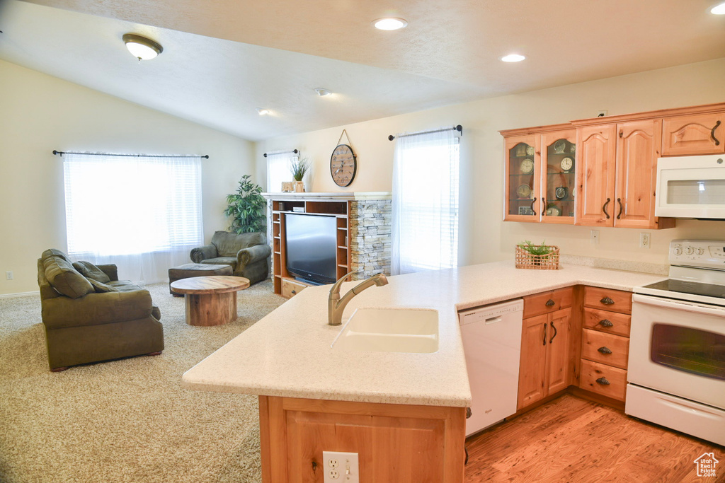 Kitchen with white appliances, a sink, a peninsula, open floor plan, and glass insert cabinets