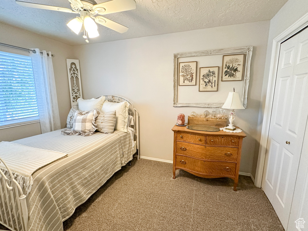 Carpeted bedroom featuring a closet, a textured ceiling, baseboards, and ceiling fan