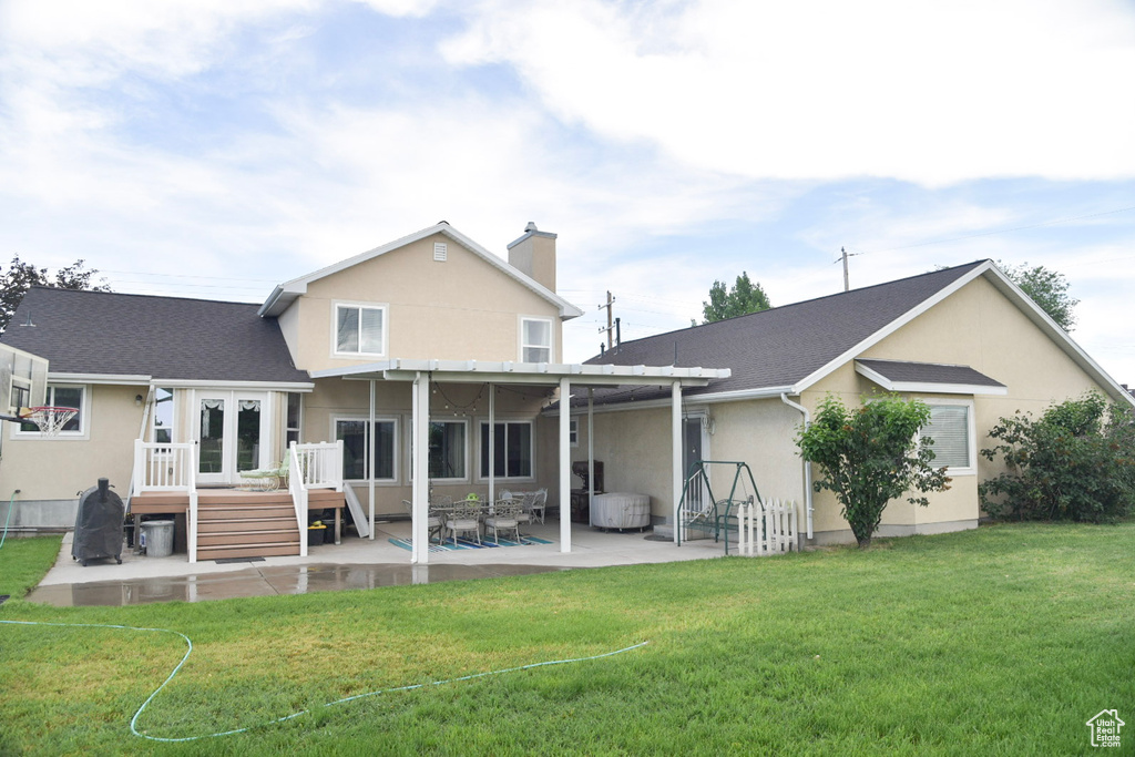 Back of property featuring a patio area, stucco siding, a deck, a chimney, and a yard