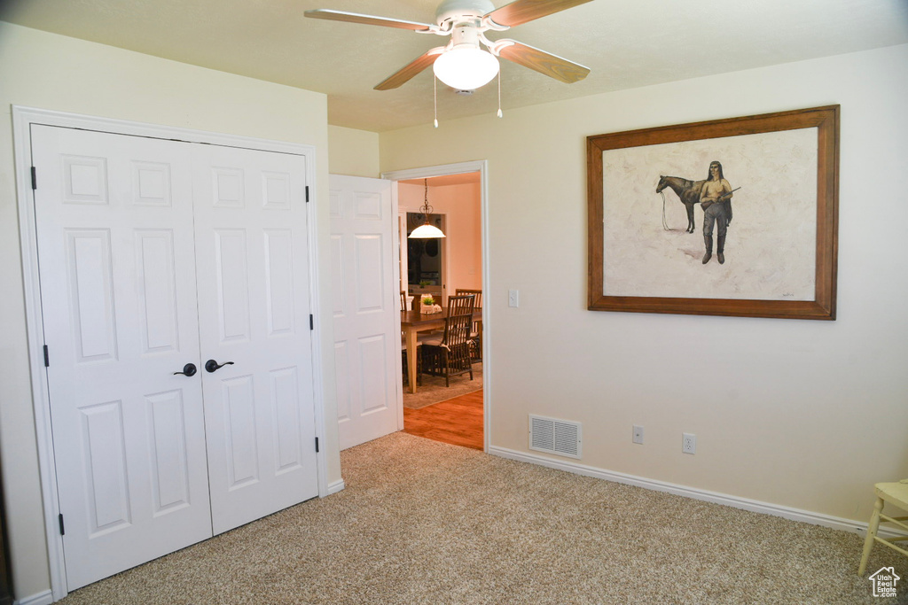 Unfurnished bedroom featuring carpet, a closet, baseboards, and ceiling fan