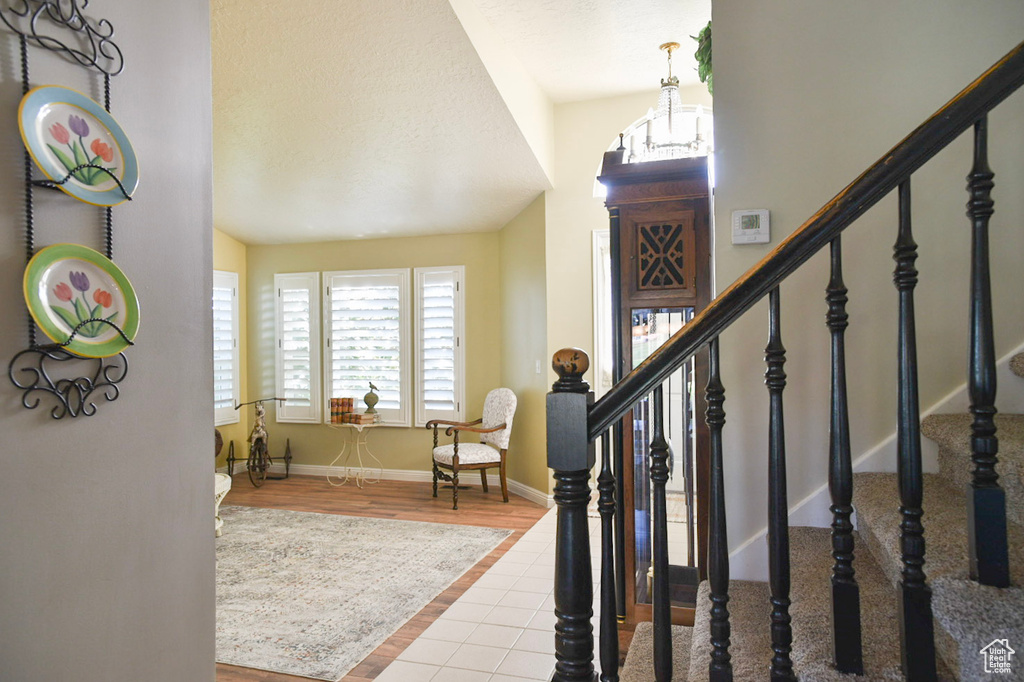 Tiled entryway featuring stairs, baseboards, and vaulted ceiling