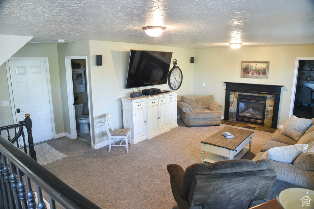 Carpeted living area featuring a textured ceiling, a fireplace with flush hearth, and baseboards