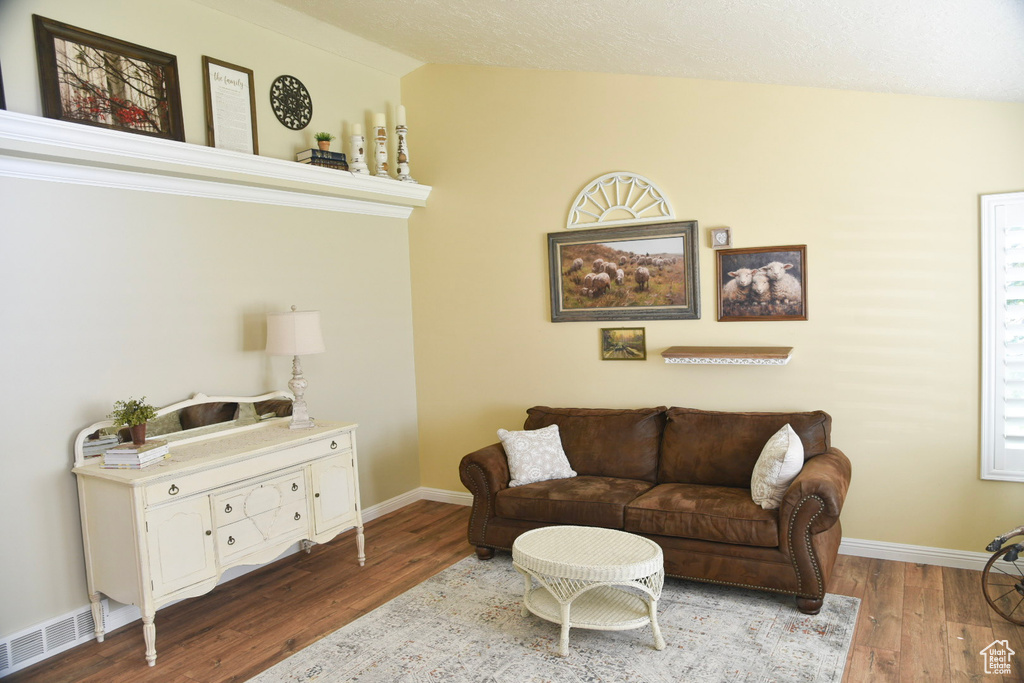 Living area with wood finished floors, lofted ceiling, and baseboards