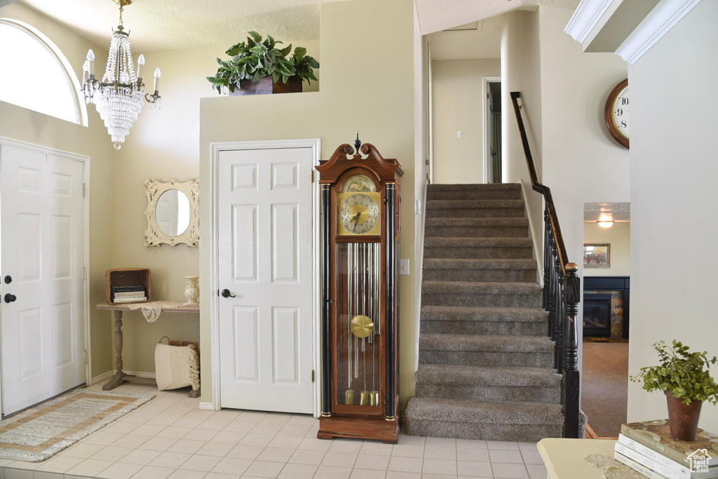 Foyer with light tile patterned flooring, stairway, a chandelier, a towering ceiling, and baseboards