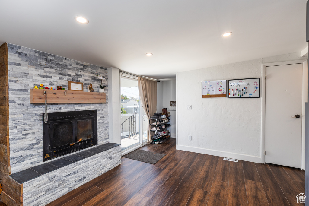 Living area featuring wood finished floors, a stone fireplace, baseboards, and recessed lighting