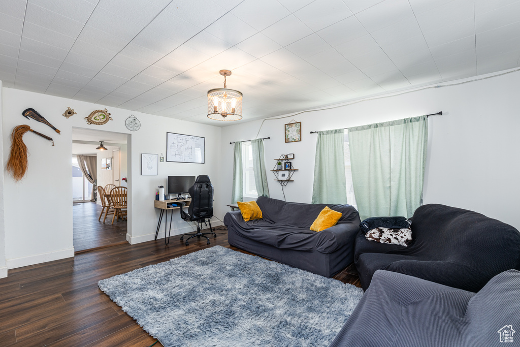 Living room with healthy amount of natural light, a chandelier, dark wood finished floors, and baseboards