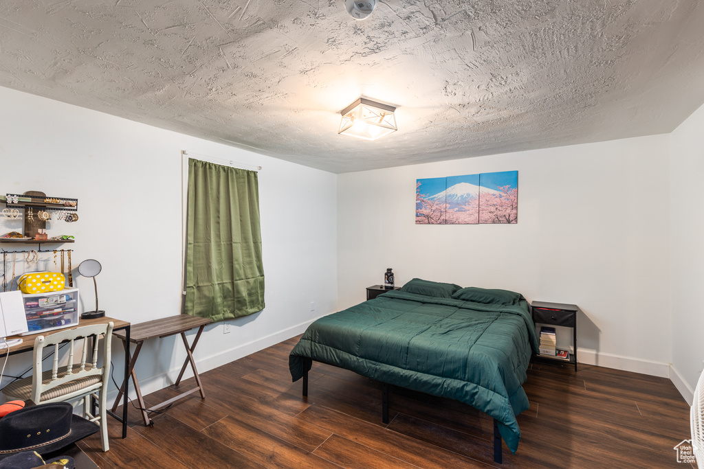 Bedroom with wood finished floors, baseboards, and a textured ceiling