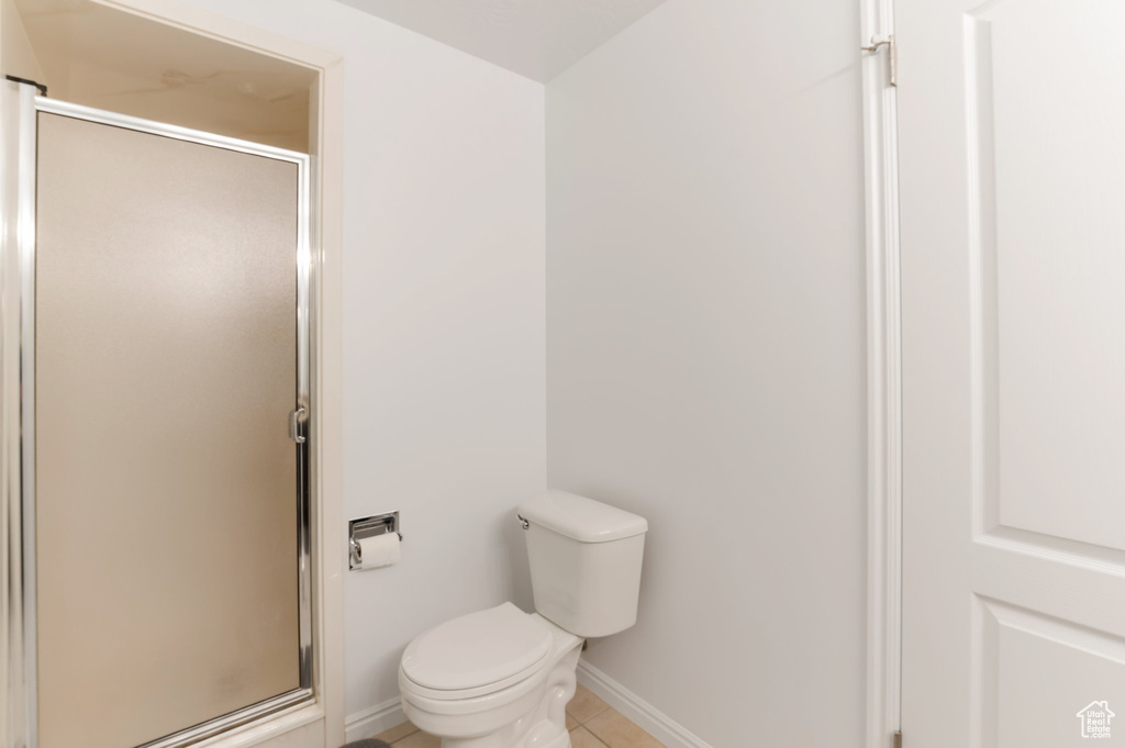 Bathroom with a stall shower, toilet, baseboards, and tile patterned flooring