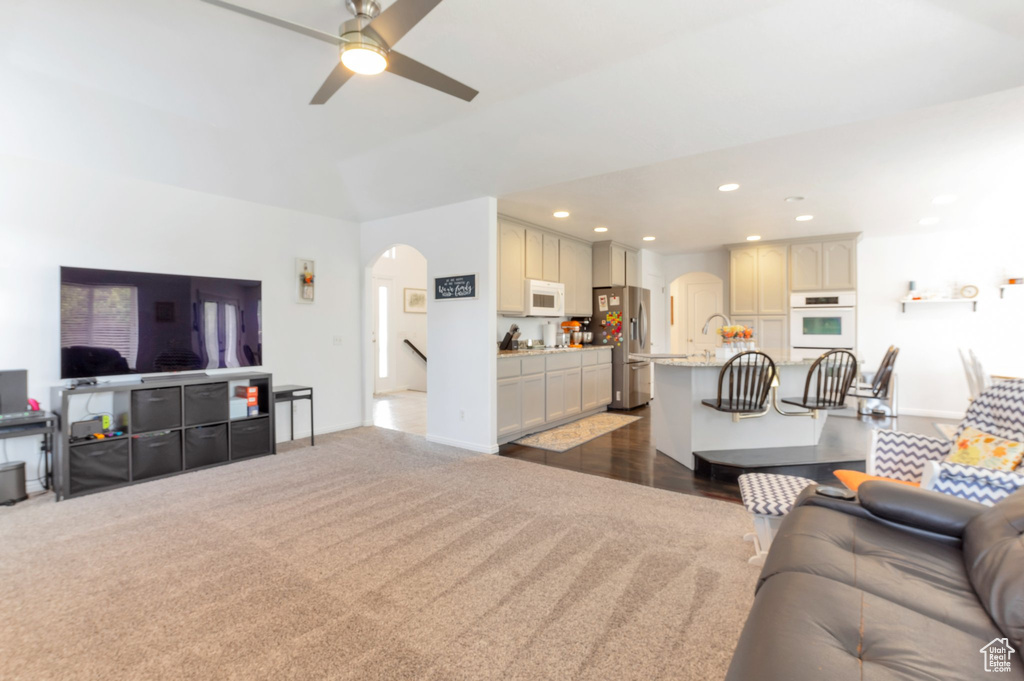 Living room with arched walkways, recessed lighting, a ceiling fan, and dark carpet